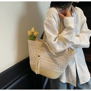 Close-up of beige crochet lace tote bag featuring delicate floral patterns and long tassels