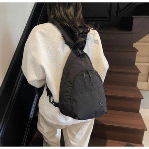 Rear view of model wearing a black water-drop nylon backpack with a sleek metal logo