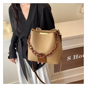 Détail du sac seau kaki en cuir litchi avec poignée en chaîne et bandoulière réglable