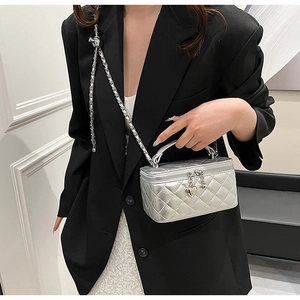 Detail of silver quilted crossbody bag with heart zipper and metal chain strap