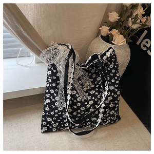 Détail du sac cabas en toile fleurie avec rubans et bordures en dentelle blanche élégante
