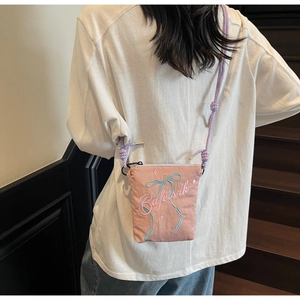 Detail view of pink canvas crossbody bag with blue bow embroidery and woven strap