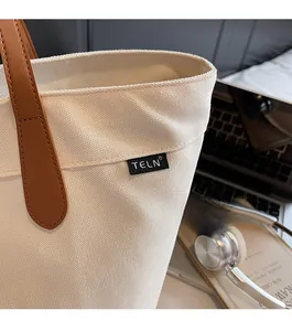 Gros plan du sac fourre-tout en toile avec poignée en cuir et étiquette de marque