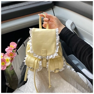 Detail of light yellow leather backpack with white lace trim and buckle flap closure