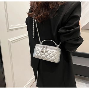 Detail of silver quilted box bag with chain strap and heart charm on black blazer