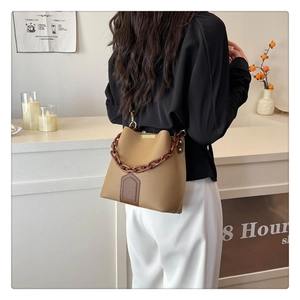 Détail du sac seau camel grainé avec chaîne ambrée et empiècement en cuir brun