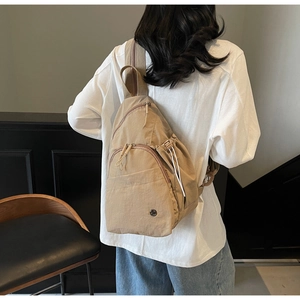 Close-up of khaki canvas chest bag with multiple zipper pockets and small metal logo