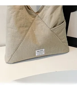 Detail of light beige nylon tote bag showing soft fabric texture and fabric label