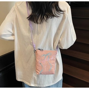 Detail of pink canvas crossbody bag with blue ribbon embroidery and purple rope strap