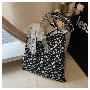 Détail d'un sac cabas en toile avec motifs de marguerites et nœud en dentelle