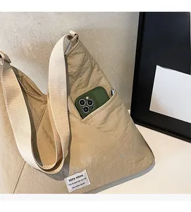 Detail of light khaki shoulder bag showing nylon texture and functional front pocket
