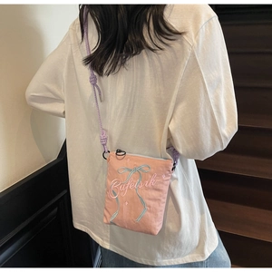 Detail of light pink canvas crossbody bag with blue ribbon embroidery and rope strap
