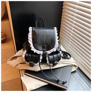 Detailed macro view of small black backpack with white lace trim and rustic textures