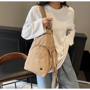 Detail of khaki nylon sling bag showing multi-pocket design and adjustable wide strap