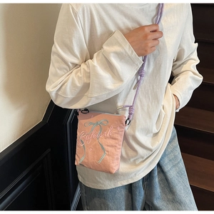 Close-up of pink canvas bucket bag with ribbon embroidery and woven rope strap