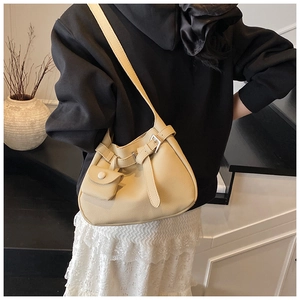 Detail view of cream hobo bag with pebble texture and mini zip pouch accessory on model