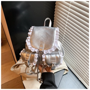 Detail of silver faux leather mini backpack with delicate white lace trim and buckle straps