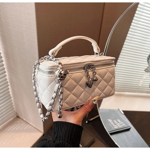 Detailed view of white quilted PU handbag featuring heart charm and silver chain strap