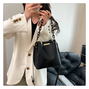 Détail du sac seau noir en cuir grainé avec chaîne épaisse et finitions dorées
