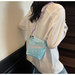Close-up of light blue canvas bucket bag with pink embroidery and braided shoulder strap