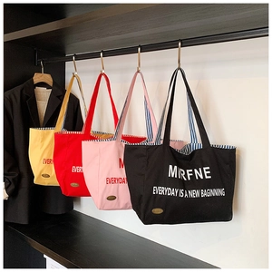 Detail view of canvas tote bags in four colors showing striped lining and side metal tag