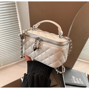 Detailed view of white quilted vanity bag featuring a heart-shaped zipper and chain strap