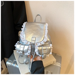 Detail of silver metallic PU leather backpack with delicate white lace trim accents