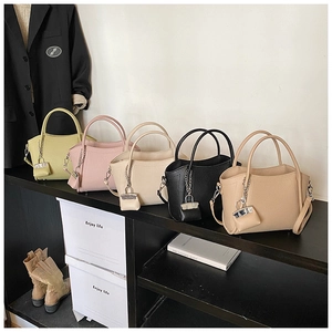 Five elegant pebbled leather handbags in pastel colors displayed on a tiered shelf