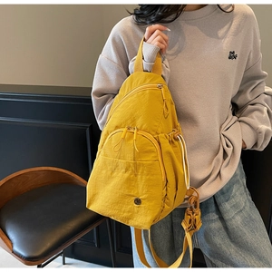 Close-up of vibrant yellow nylon crossbody backpack with zip pockets and crinkled texture