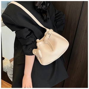Close-up of beige lychee-patterned bucket bag with mini coin purse on a model