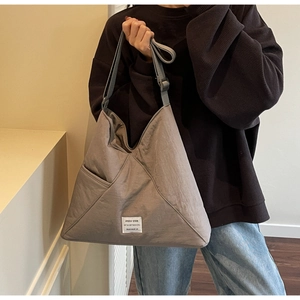 Detail view of grey nylon hobo bag featuring triangle stitching and a white woven label