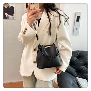 Détail du sac seau noir grainé avec accents dorés et poignée à chaîne épaisse