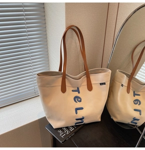 Détail du sac cabas en toile avec broderie TELN bleue et bandoulière en cuir marron