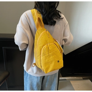 Macro shot of bright yellow nylon crossbody chest bag showing texture and adjustable strap