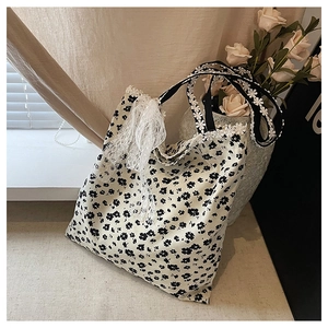 Gros plan du sac cabas en toile fleurie beige avec nœud en dentelle et broderie de fleurs