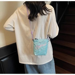 Detail of blue canvas crossbody bucket bag with pink embroidery and purple rope strap