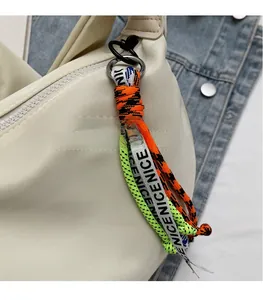 Close-up of off-white nylon dumpling bag with colorful braided cord and NICE charm