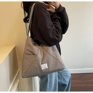 On-body view of mocha nylon tote bag with geometric stitching and white woven label