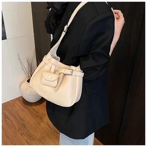 Close-up of beige lychee texture leather shoulder bag worn by model in black suit