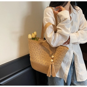 Detailed close-up of handmade woven straw bag with hollow crochet texture and tassel charm