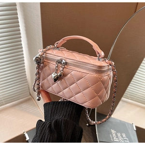 Detailed shot of pink quilted mini bag with silver chain and heart-shaped pendant
