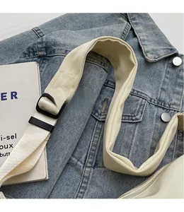 Detail of adjustable smooth cream shoulder strap with black buckle on a modern fabric bag