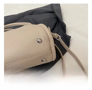 Close-up of beige pebble leather bucket bag showing silver studs and fine stitching