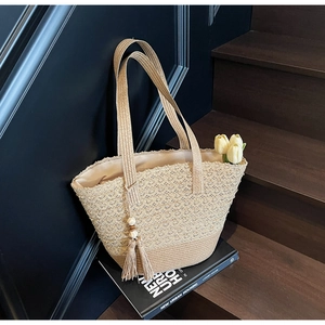 Detailed macro view of hollow crochet straw bucket bag with wooden bead tassels