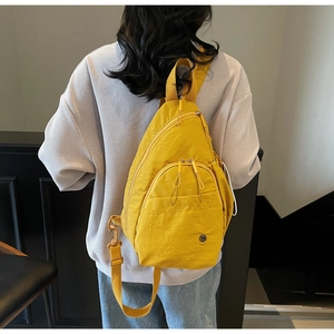 Detailed back view of bright yellow nylon mini backpack on grey hoodie outfit