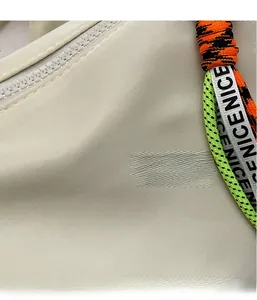 Detail of light beige nylon fabric with a colorful braided zipper pull and NICE text