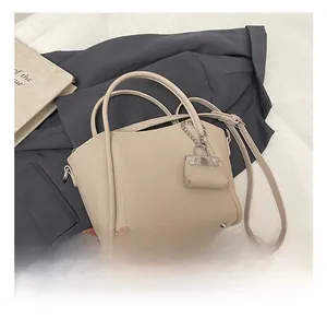 Close-up of beige bucket bag with litchi grain texture and mini charm detail