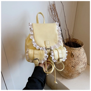 Detail of light yellow PU backpack with white lace trim and vintage metal buckles