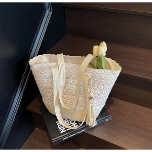 Close-up of cream lace weaving and straw details with a beaded tassel on the bucket bag