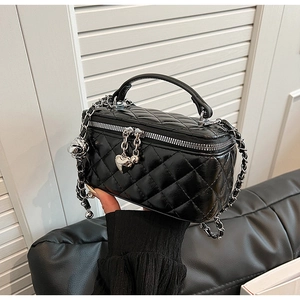 Close-up of black quilted leather vanity bag with silver zippers and heart metal charm